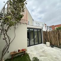 Aanbouw met glazen pui en witte gevel aan een tuinzijde