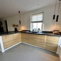 Keuken in L-opstelling met houten fronten onder een schuin dak
