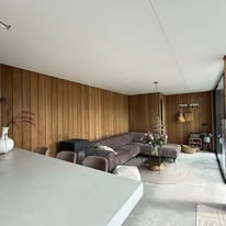 Loungehoek met houten plafond en wandbekleding in de veranda