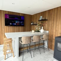 Bar met houten wandbekleding en barkrukken in de veranda