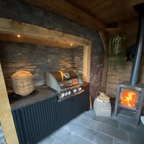 Buitenkeuken met haard, barbecue en natuurstenen wand